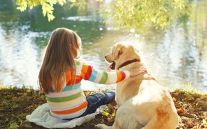 labrador sitzt mit maedchen am fluss