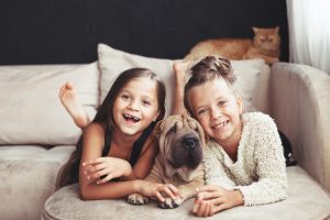 zwei mädchen mit shar pei hund und katze auf einem sofa